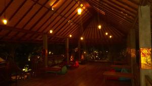 a room with a wooden floor and a roof with lights at Rich Farmer Eco House and Yoga in Pemuteran