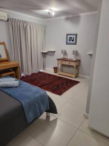 a room with a bed and a table in it at Fynbosrus on Grotto in Hermanus