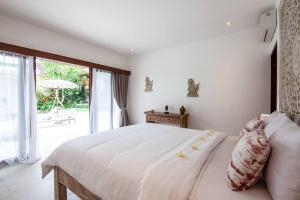 a bedroom with a white bed and a large window at Villa Matigo Canggu in Canggu +34 photos