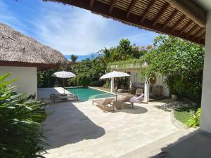 a patio with chairs and umbrellas and a swimming pool at Villa Matigo Canggu in Canggu