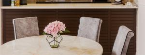 een vaas met roze bloemen op een tafel met twee stoelen bij SPRINGHILL RESORT in Cameron Highlands