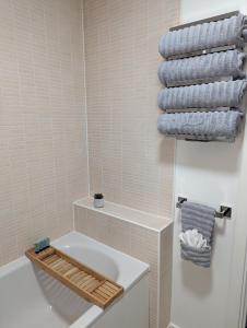 a bathroom with a white tub and a toilet and towels at Modern 2 Bed house - HS2, NEC & Birmingham Airport in Marston Green