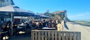a group of people sitting at tables on a beach at Les Fregates in Veulettes-sur-Mer
