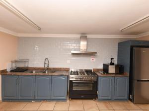 a kitchen with blue cabinets and a sink and a refrigerator at Blue Sands Guest House in Pietermaritzburg