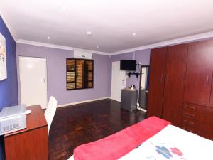 Schlafzimmer mit lila Wänden, einem Bett und einem Schreibtisch in der Unterkunft Blue Sands Guest House in Pietermaritzburg