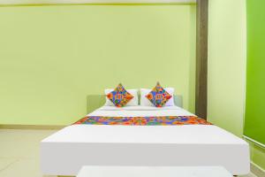 a large white bed with colorful sheets and pillows at FabExpress Airport Stay Inn in Hyderabad