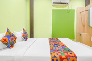 um quarto com uma cama branca e almofadas coloridas em FabExpress Airport Stay Inn em Hyderabad