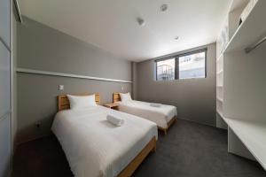 2 camas en una habitación pequeña con ventana en Bluebird Apartments by The Hakuba Collection, en Hakuba
