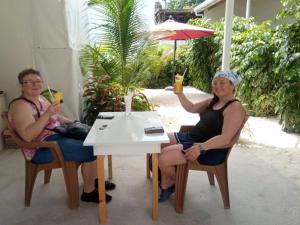 Thoddoo Garden inn في ثودو: يجلس شخصان على طاولة مع المشروبات