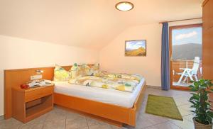 Schlafzimmer mit einem Bett mit einem Tisch und einem Fenster in der Unterkunft Niederhaeusererhof in Pfalzen