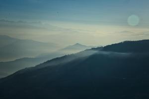 a misty view of a mountain range with trees at Hotel Mystic Mountain in Nagarkot