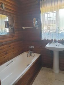 a bathroom with a bath tub and a sink at Deep Blue Guest House in Amanzimtoti