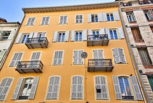 un bâtiment jaune avec balcon et horloge. dans l'établissement Very nice 2p with all comfort, city center Ac/wifi, à Nice