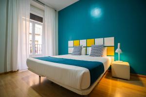 een slaapkamer met een groot bed met een blauwe muur bij Smartr Madrid Chueca in Madrid