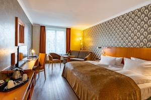 ゲルリッツにあるパークホテル ゴルリッツのベッドとデスクが備わるホテルルームです。