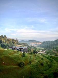 a house on top of a grassy hill at Talula Hill Farm Resort in Kluang