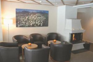 a waiting room with chairs and tables and a fireplace at Hamarøy Hotel in Innhavet