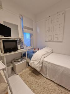 a white bedroom with a bed and a television at The White House in Waltham Cross