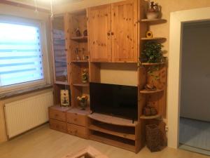 a living room with a flat screen tv in a wooden cabinet at Ferienwohnung Ober Widdersheim in Nidda