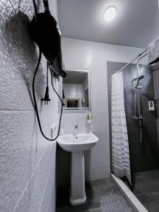 a white bathroom with a sink and a shower at Котедж з власною фінською сауною in Poltava