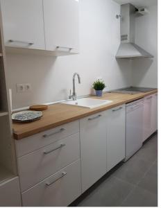 eine Küche mit weißen Schränken und einem Waschbecken in der Unterkunft Moderno apartamento con piscina disponible según restricciones sequía in Torremolinos
