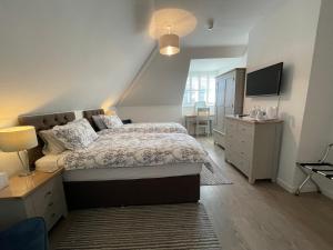 a bedroom with a bed and a dresser and a television at Cotswold Hare in Cirencester