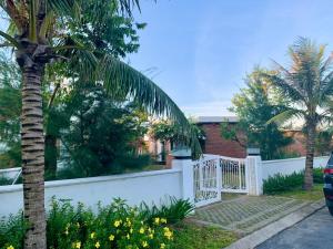 a house with a white fence and a palm tree at Hoa Tien Paradise Villa in Ha Tinh