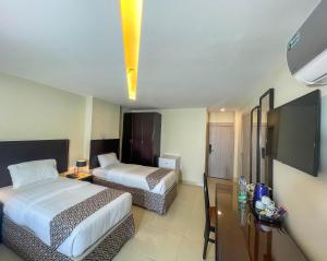Habitación de hotel con 2 camas y TV de pantalla plana. en Dweik Hotel 2, en Áqaba