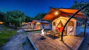 a row of tents with a deck with a fire at Club Lespia in Pocheon Baegun Valley in Pocheon