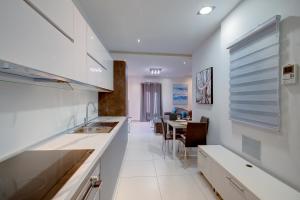 a kitchen with white counters and a table with chairs at Idyllic Apartment just off the Promenade in Sliema
