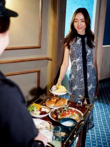 una donna in piedi di fronte a un buffet di cibo di The Coach Hotel Sukhumvit - Asok BTS Bangkok by Compass Hospitality a Bangkok