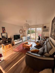 ein Wohnzimmer mit einem Sofa und einem Tisch in der Unterkunft Appart 2 chambres 17 min de Paris in Rosny-sous-Bois