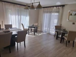 a dining room with tables and chairs and windows at Ashwood The Ridge Boutique Hotel in Bloemfontein