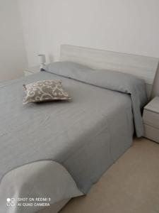 uma cama cinzenta com uma almofada em cima em Patacchella House em Ostuni