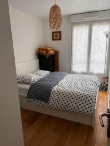 Schlafzimmer mit einem Bett mit einer schwarzen und weißen Bettdecke in der Unterkunft Appart 2 chambres 17 min de Paris in Rosny-sous-Bois