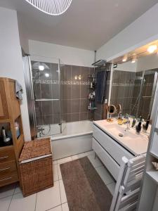 ein Bad mit einer Badewanne, einem Waschbecken und einer Dusche in der Unterkunft Appart 2 chambres 17 min de Paris in Rosny-sous-Bois