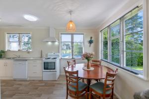 a kitchen with a table and chairs and windows at Carrington Countryside - New Plymouth Holiday Home in New Plymouth