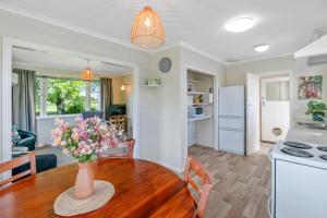 eine Küche und ein Wohnzimmer mit einem Tisch mit einer Blumenvase in der Unterkunft Carrington Countryside - New Plymouth Holiday Home in New Plymouth + 18 Fotos