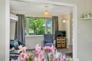 a living room with a chair and a window at Carrington Countryside - New Plymouth Holiday Home in New Plymouth