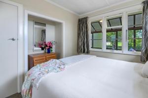 a bedroom with a white bed and two windows at Carrington Countryside - New Plymouth Holiday Home in New Plymouth