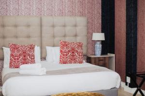 Ashwood The Ridge Boutique Hotel في بلومفونتين: غرفة نوم مع سرير أبيض كبير مع وسائد حمراء