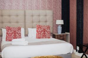 a bedroom with a large white bed with red pillows at Ashwood The Ridge Boutique Hotel in Bloemfontein