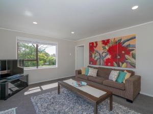 a living room with a couch and a tv at Purely Pauanui - Pauanui Holiday Home in Pauanui