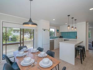 a kitchen and dining room with a table and chairs at Purely Pauanui - Pauanui Holiday Home in Pauanui