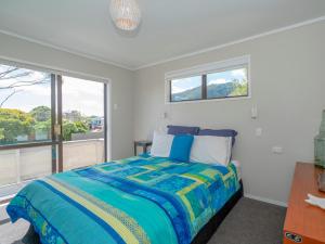 a bedroom with a bed and a large window at Purely Pauanui - Pauanui Holiday Home in Pauanui