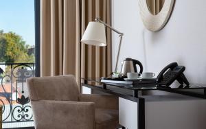 a desk and a chair with a lamp and a phone at Mercure Tashkent in Tashkent