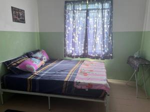 a small bed in a room with a window at Maju Homestay in Gerik