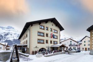 ein großes Gebäude im Schnee mit Bergen im Hintergrund in der Unterkunft Albana Hotel Silvaplana in Silvaplana