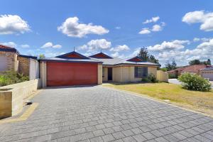 a house with a red garage on a driveway at Daydream by the Sea! in Mandurah