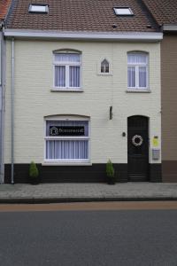 une maison blanche avec deux fenêtres et une porte dans l'établissement Gastenkamers Boussemaere, à Ichtegem